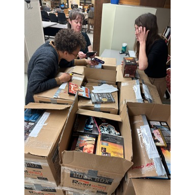 People open boxes of DVDs and VHS tapes.