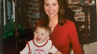 A baby sits on another person's lap.