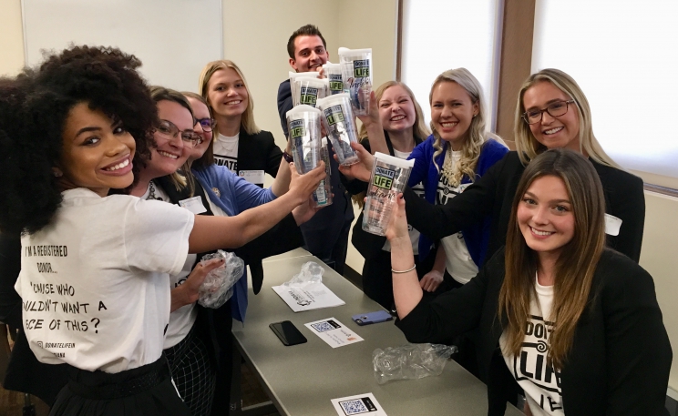 Students pose wearing T-shirts and holding cups they produced as part of their campaign.