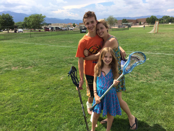 Fuller with two girls on a lacrosse field