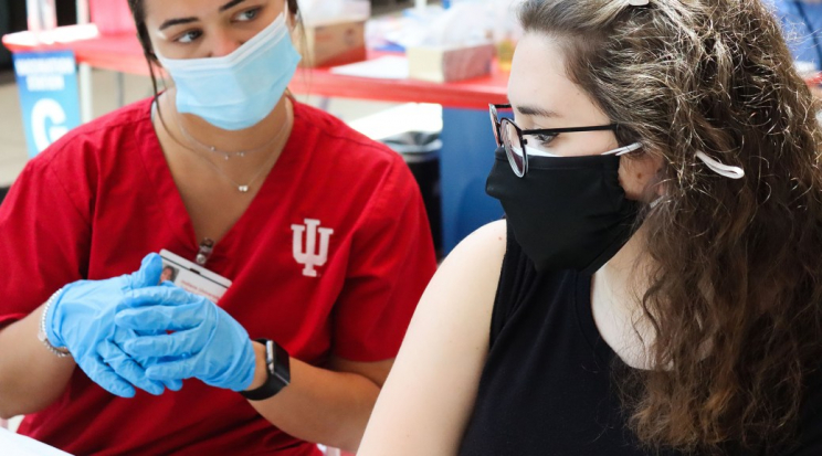 Photo of a nurse looking at a student receiving a COVID vaccine