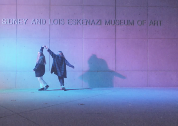 Two women dance in front of the art museum at IU.