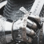 Closeup of hand holding sword in armor