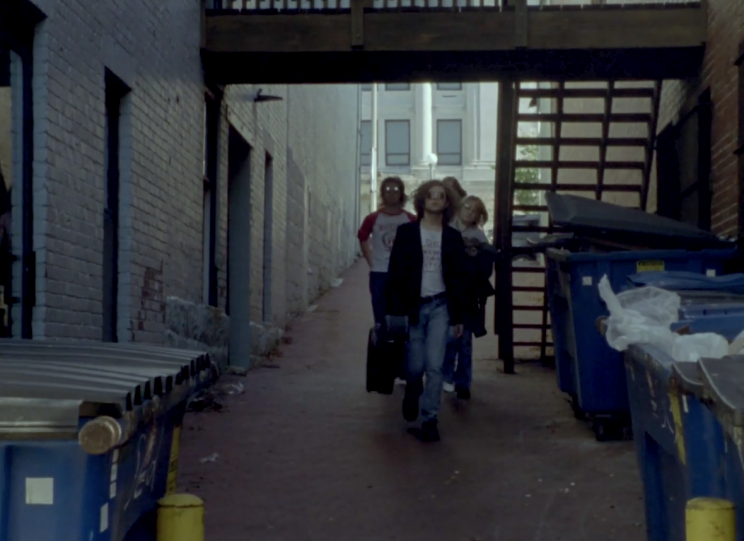 4 bandmates walk down an alley