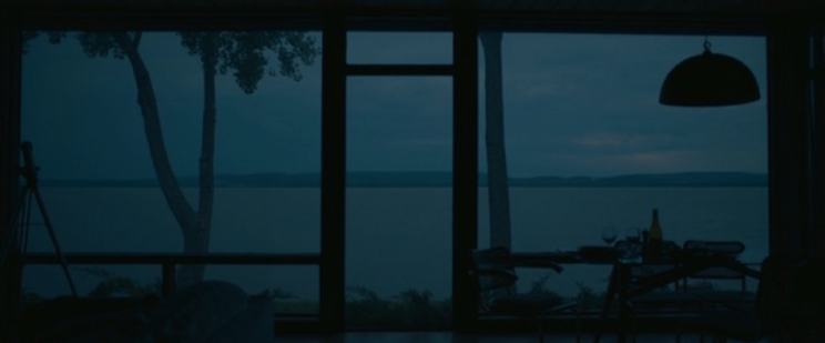 A window overlooking a lake. The sky is dark and gray.