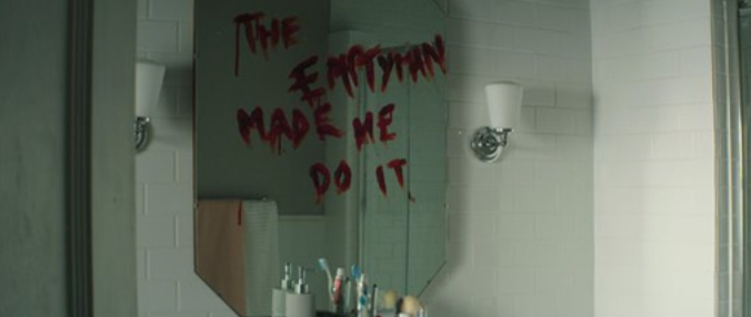 A mirror with bloody writing on it. Text: The empty man made me do it.