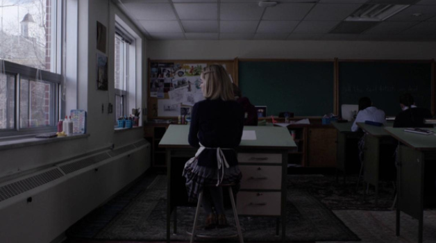 A woman stands in a classroom.