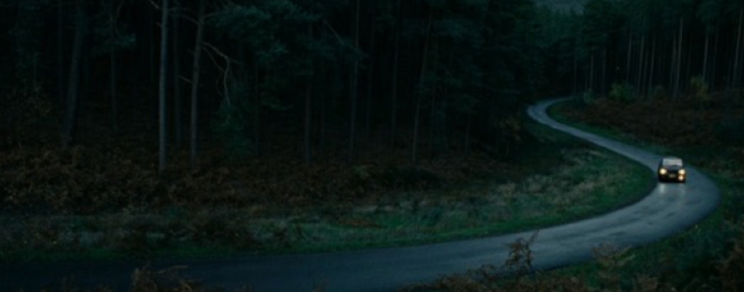 A car drives on a lone road.