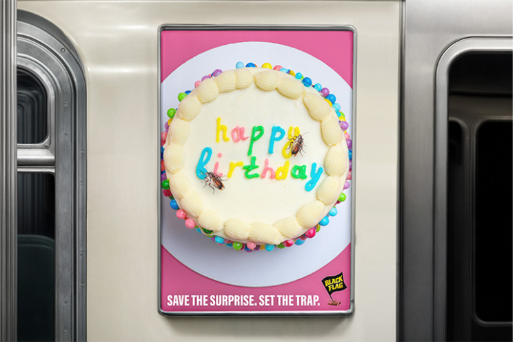 Photo of a transit advertisement. The ad has a photo of a birthday cake with a roach crawling on the cake. the text for this ad reads "Save the surprise. Set the trap."